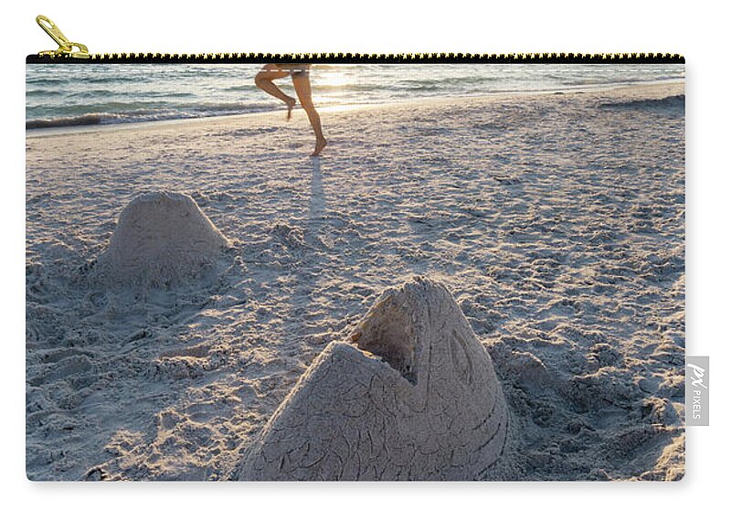 Anna Maria Island Zip Pouch featuring the photograph A woman catches a flying disk near a sand sculpture of a fish he by William Kuta