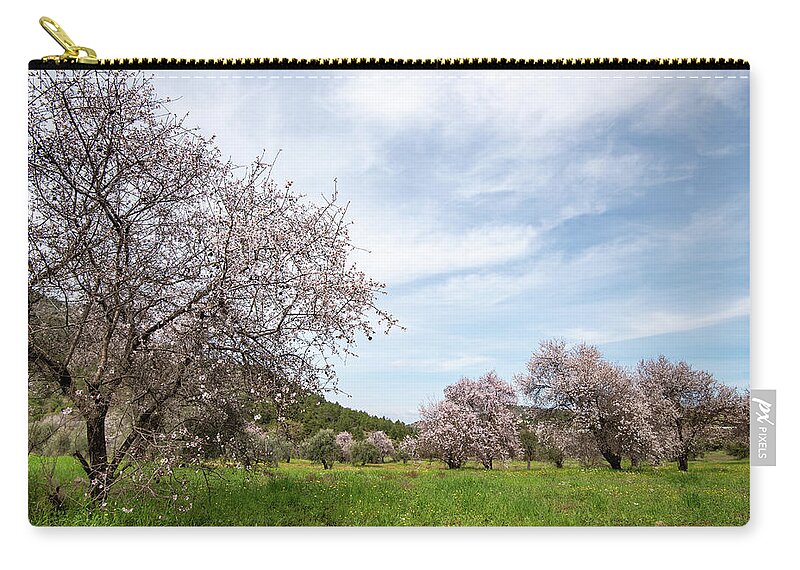 Spring Carry-all Pouch featuring the photograph Almond trees bloom in spring against blue sky. by Michalakis Ppalis
