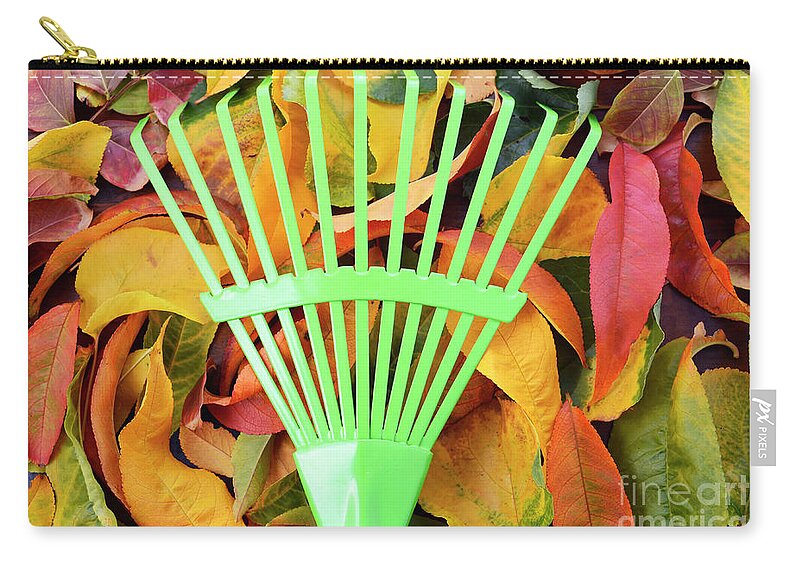 Autumn Zip Pouch featuring the photograph Autumn Fall Background with Green Rake. by Milleflore Images