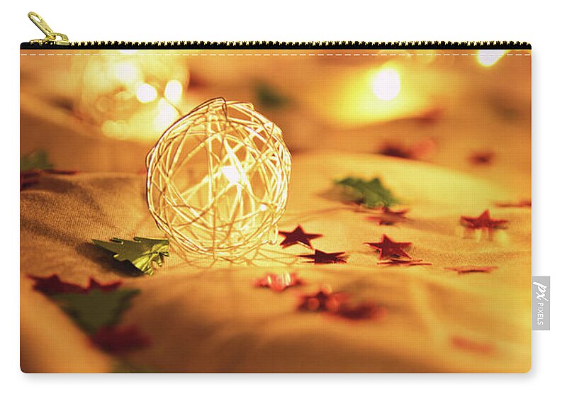 Lights Zip Pouch featuring the photograph Blurred golden Christmas lights with decorations on rumpled bed by Mendelex Photography