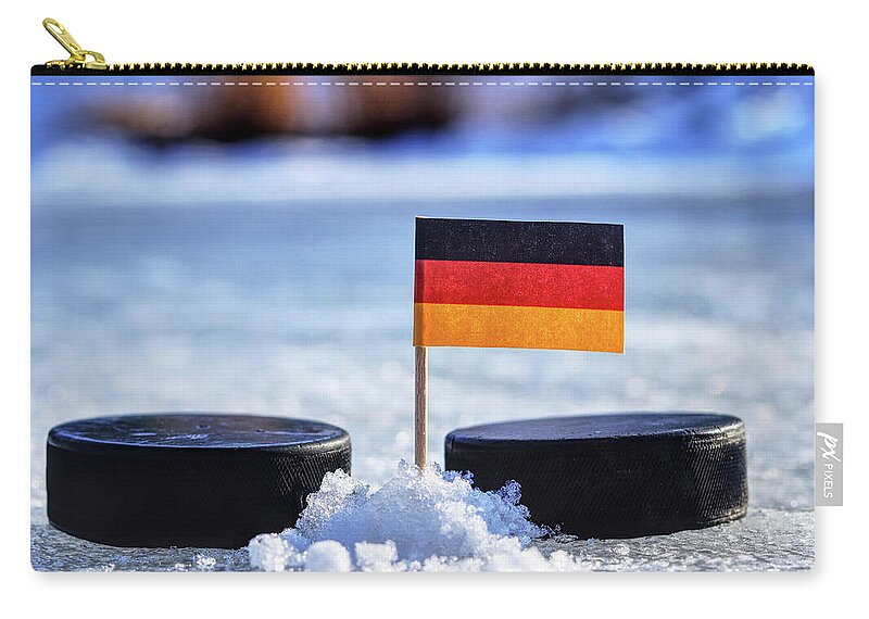 Germany Zip Pouch featuring the photograph Germany flag on toothpick between two hockey pucks. Winter classic. Flag on frozen pond on unkempt ice. Traditional pucks for international matches. by Vaclav Sonnek