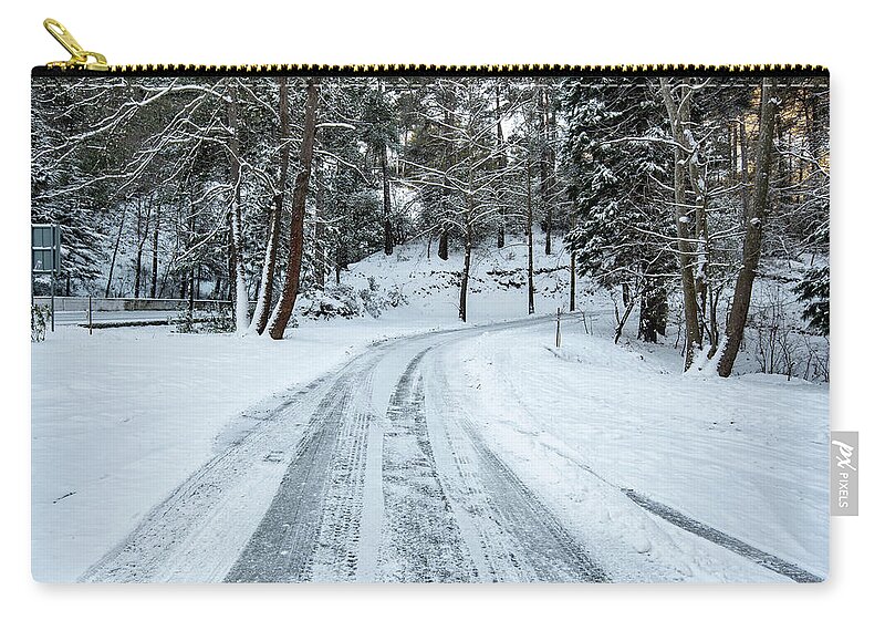 Frozen Road Zip Pouch featuring the photograph Icy slippery dangerous road in winter in the forest. Snowy mountains snowstorm. by Michalakis Ppalis