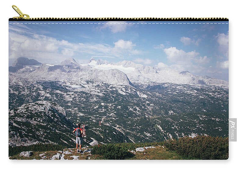 Sportive Zip Pouch featuring the photograph Man with a backpack looks at the Dachstein massif by Vaclav Sonnek