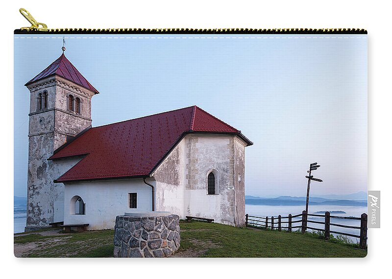 Saint Zip Pouch featuring the photograph Morning glow over church by Ian Middleton