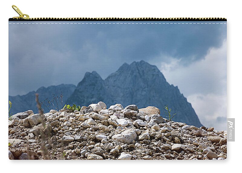 Mountains Zip Pouch featuring the photograph Stony hill with plants in front of a mountain range. by Bernhard Schaffer