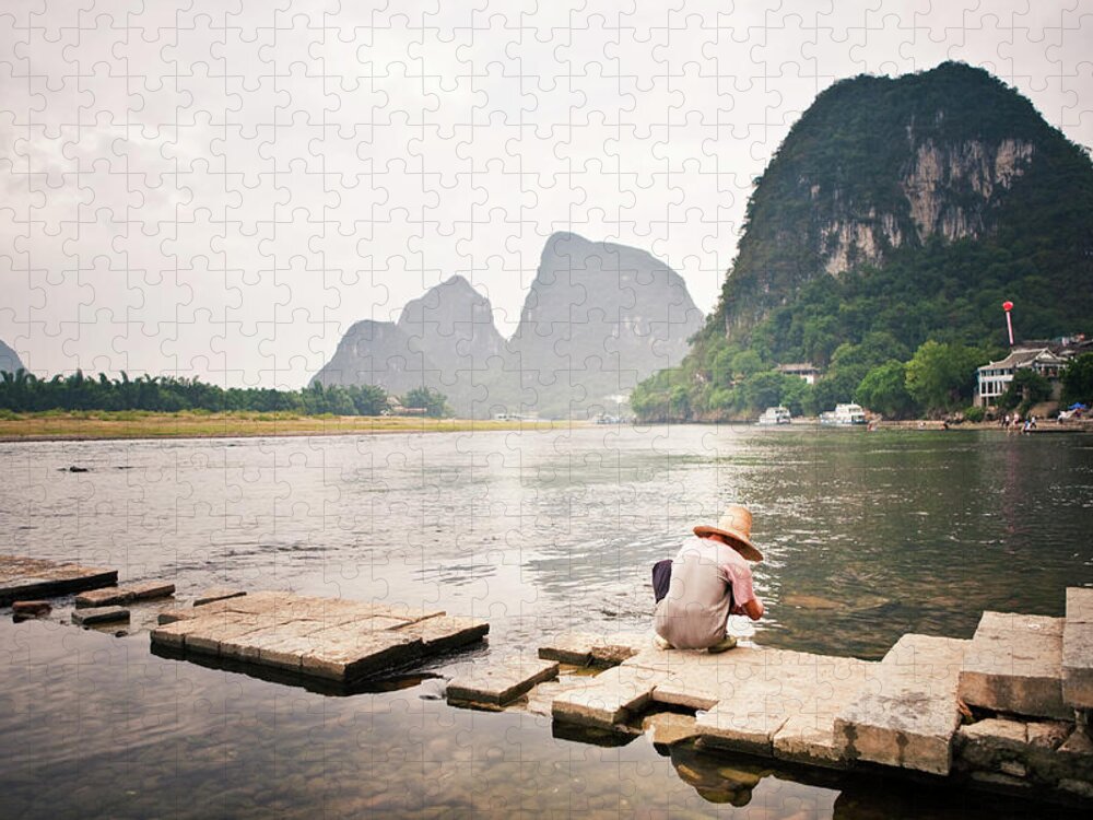 Yangshuo Jigsaw Puzzle featuring the photograph Man Squatting By Li River by Merten Snijders