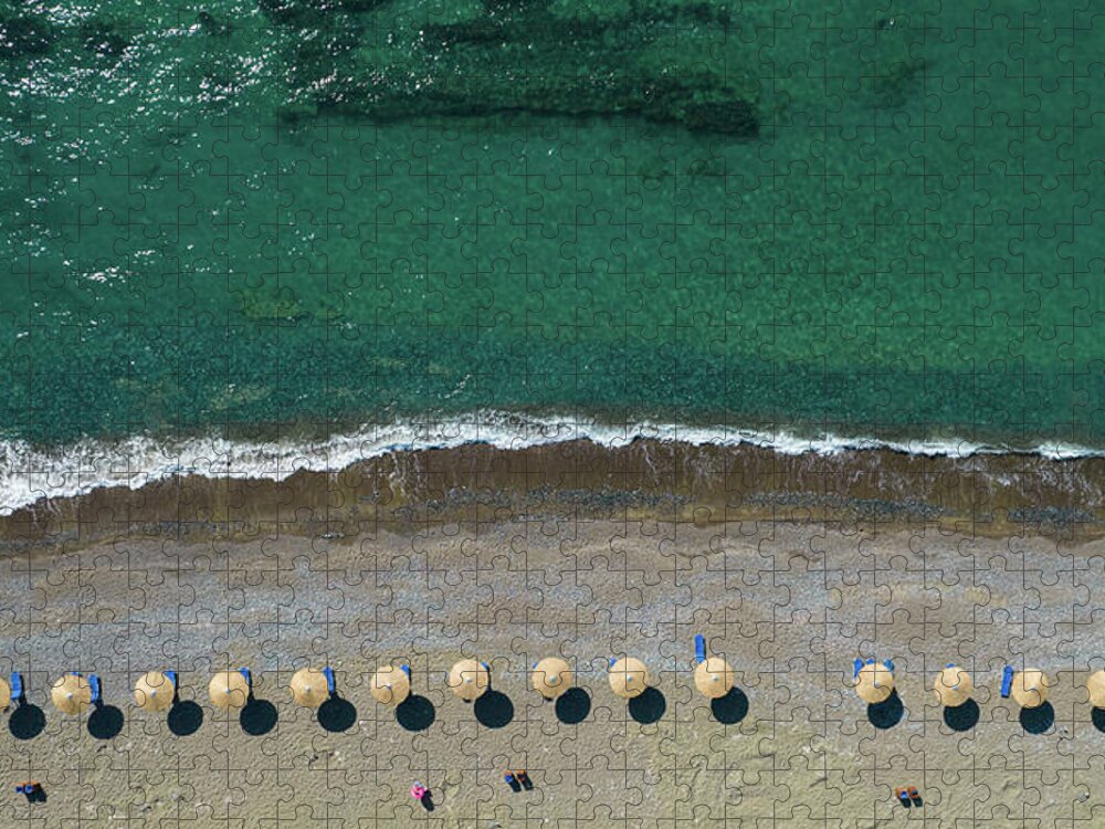 Summertime Jigsaw Puzzle featuring the photograph Aerial view from a flying drone of beach umbrellas in a row on an empty beach with braking waves. by Michalakis Ppalis
