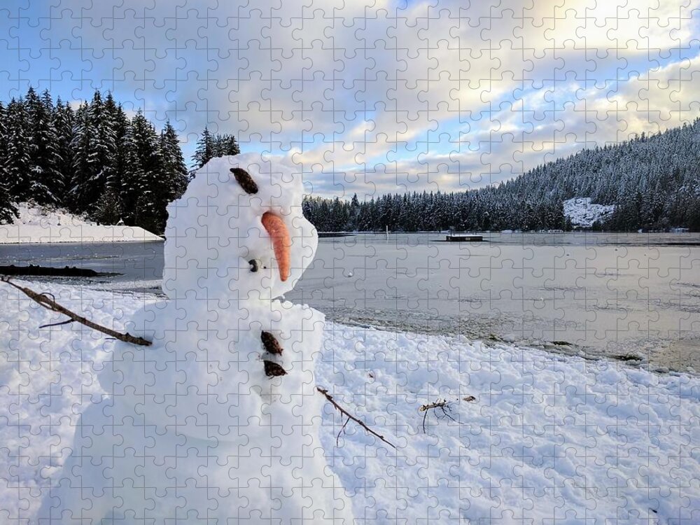Closeup shot of a deformed snowman with a frozen lake in the background  during winter Jigsaw Puzzle