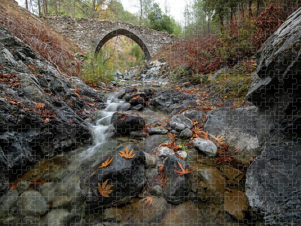 Autumn Jigsaw Puzzle featuring the photograph Medieval stoned bridge with water flowing in the river in autumn. by Michalakis Ppalis