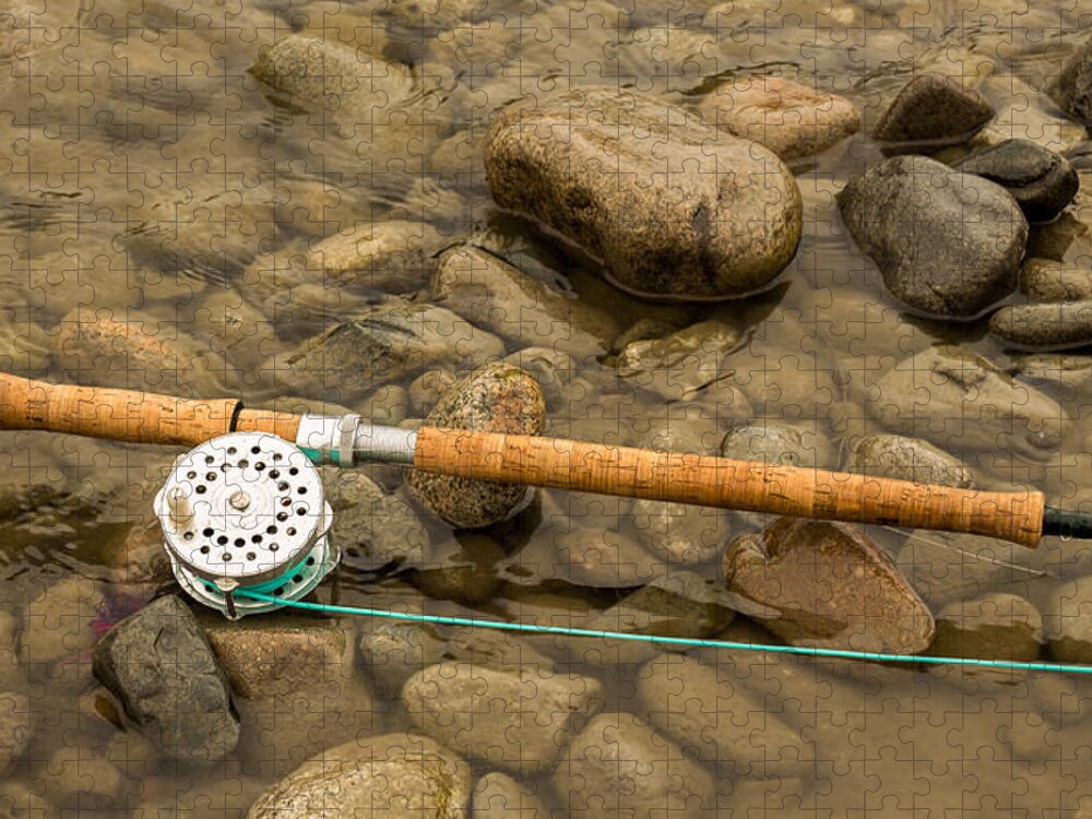 Spey fly rod and reel resting on wet rocks beside a river. Jigsaw