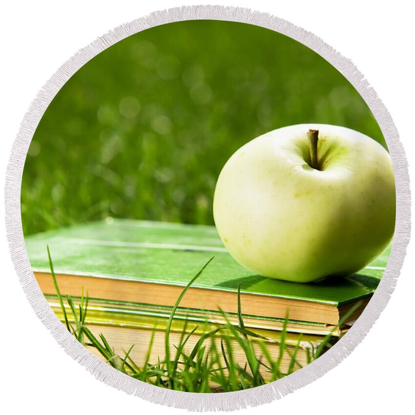 Apple Round Beach Towel featuring the photograph Apple on pile of books on grass by Michal Bednarek