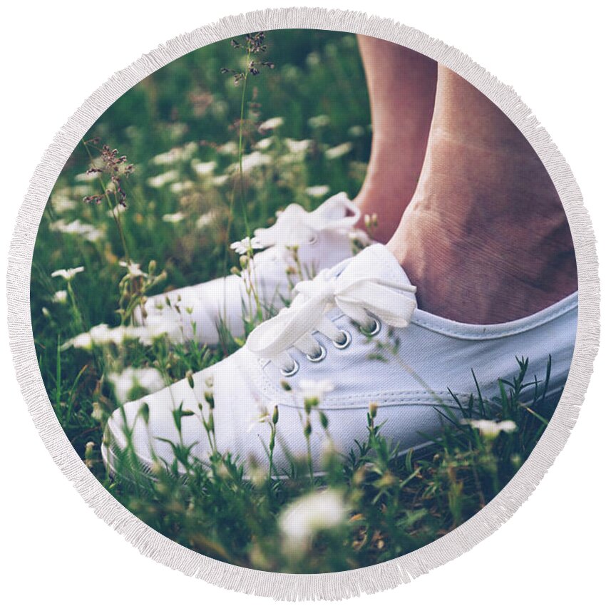 Woman Round Beach Towel featuring the photograph Woman in sneakers standing on meadow with flowers. by Michal Bednarek