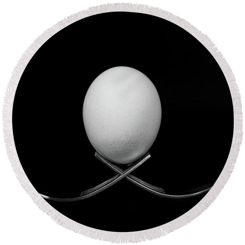 Egg Round Beach Towel featuring the photograph White egg resting on two metal and shiny forks on a black backg by Michalakis Ppalis