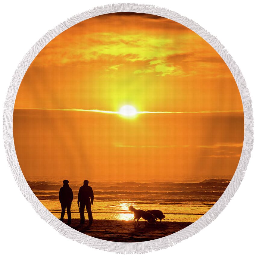 Man Round Beach Towel featuring the photograph A couple walking their dog at sunset on Ynyslas beach, Wales UK by Keith Morris