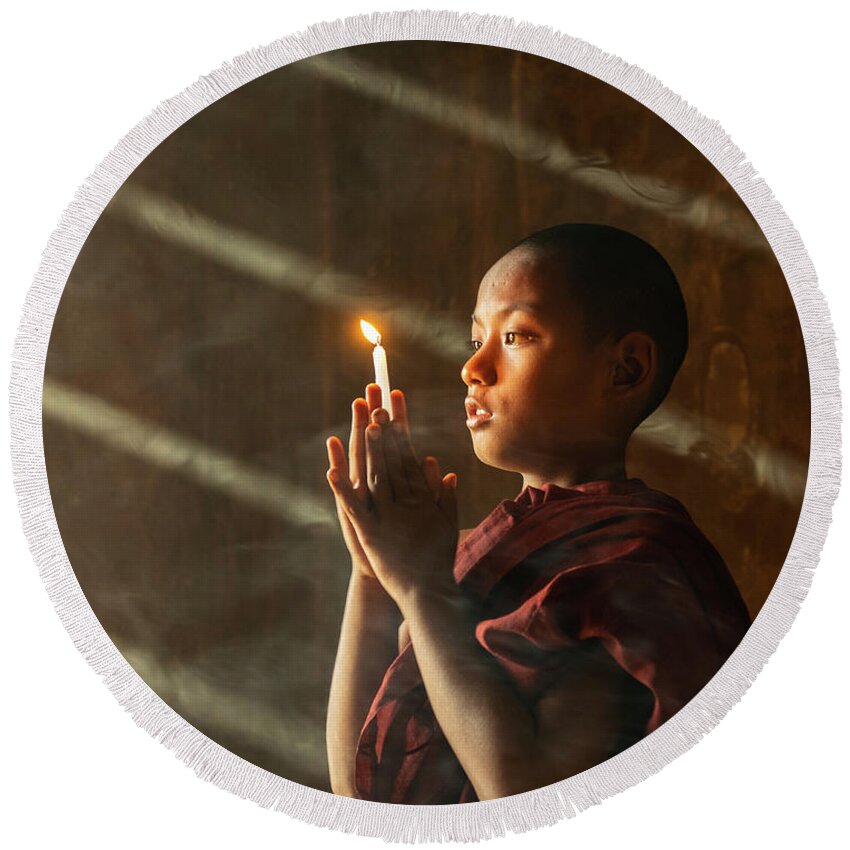 Boy Round Beach Towel featuring the photograph A Novice Monk With Candle In Prayer In Temple by Ann Moore