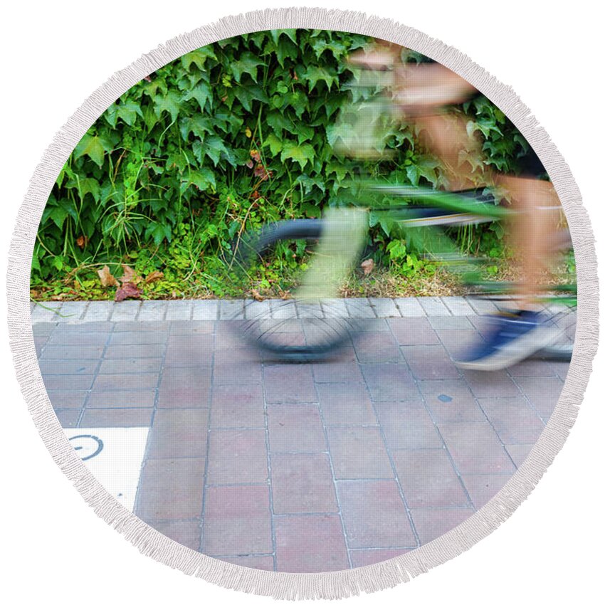 Action Round Beach Towel featuring the photograph Motion blurred cyclists to show speed, driving along a bike lane by Joaquin Corbalan
