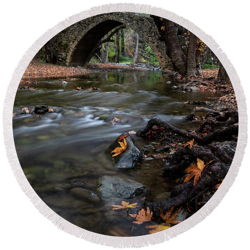 Autumn Round Beach Towel featuring the photograph Autumn landscape with river flowing under a stoned bridge by Michalakis Ppalis