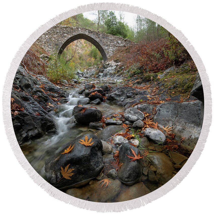 Autumn Round Beach Towel featuring the photograph Medieval stoned bridge with water flowing in the river in autumn. by Michalakis Ppalis