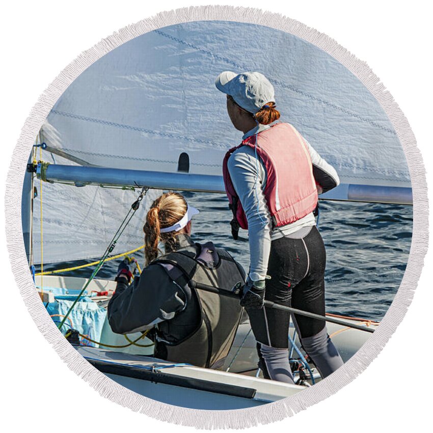 Female Round Beach Towel featuring the photograph Two girls one standing other sitting sailing a racing skiff clos by Geoff Childs