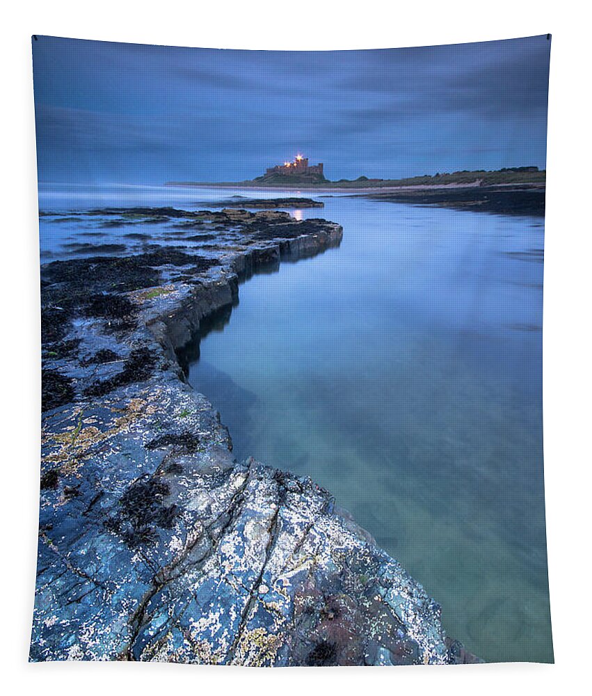 Bamburgh Castle Tapestry featuring the photograph Bamburgh Castle blue hour from the rocks after dark by Anita Nicholson