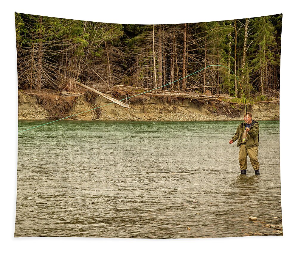 A man hooked into a fish while fly fishing in British Columbia