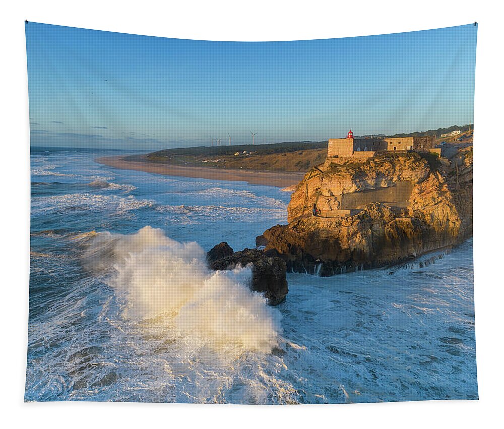 Nazare Tapestry featuring the photograph Lighthouse and big waves at in Nazare by Mikhail Kokhanchikov