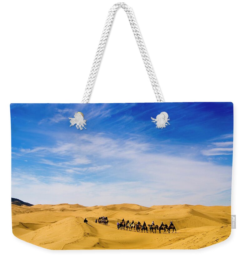People Weekender Tote Bag featuring the photograph Tourists Riding Camels On Desert Dunes #1 by Aldo Pavan