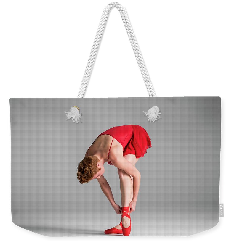 Ballet Dancer Weekender Tote Bag featuring the photograph Ballerina In Red Adjusting Point Shoes by Nisian Hughes