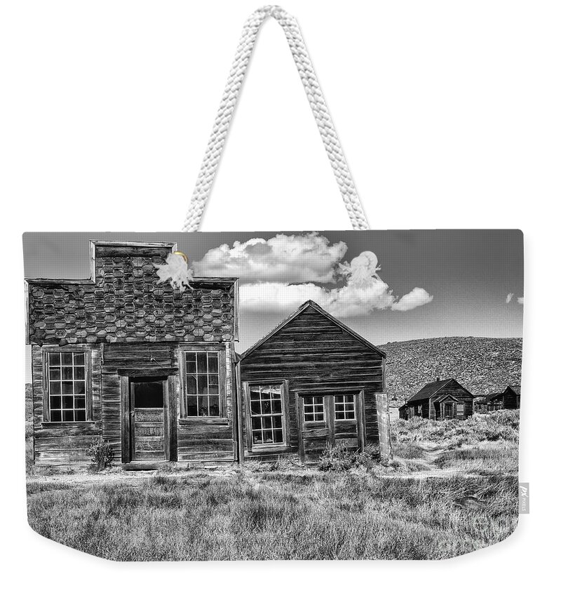 Black & White;black + White;monochrome;black And White;architecture;detail;details;cabins;structures;wood;windows;doors;door;window;buildings;dilapidated;rundown;abandoned;forlorn;derelict;empty;sandra Bronstein;clouds;doorways;entrances;old West;out West;bodie;ghost Town;ghost Towns;california;gold Rush Days;mining;houses;house;residence;horizontal;fine Art Photography;iconic;travel;tourism;historical;state Park;popular;dated;unoccupied;panes;glass;western United States;canvas; Weekender Tote Bag featuring the photograph Days of Glory Gone by Sandra Bronstein