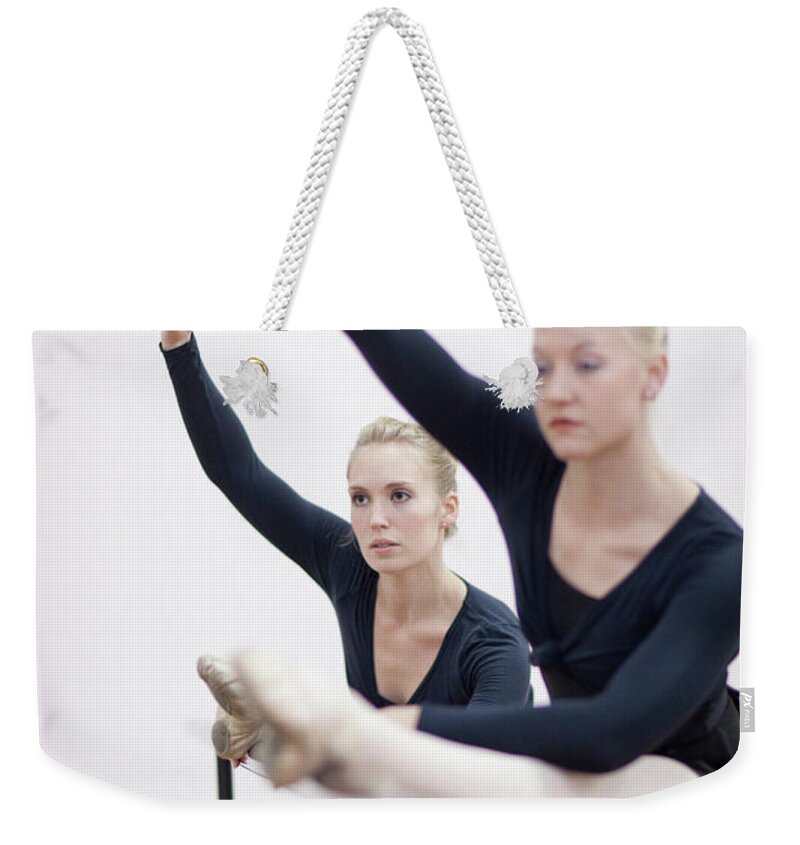 Ballet Dancer Weekender Tote Bag featuring the photograph Female Ballerinas Stretching At The by Zero Creatives