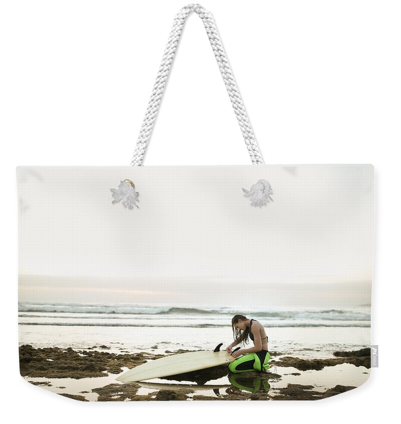 Three Quarter Length Weekender Tote Bag featuring the photograph Girl Preparing Surfing Board On Rocky by Stanislaw Pytel