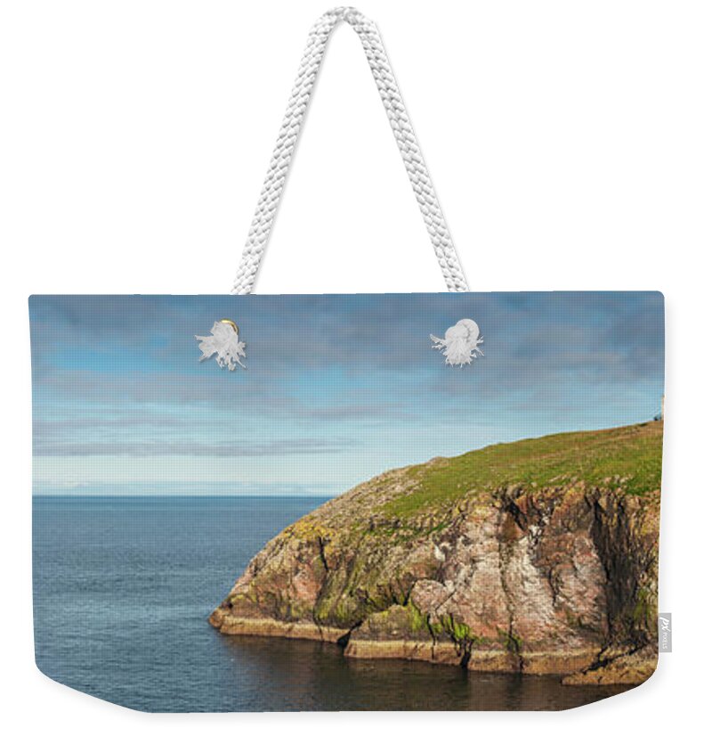 Water's Edge Weekender Tote Bag featuring the photograph Lighthouse On Cliff Overlooking Blue by Fotovoyager
