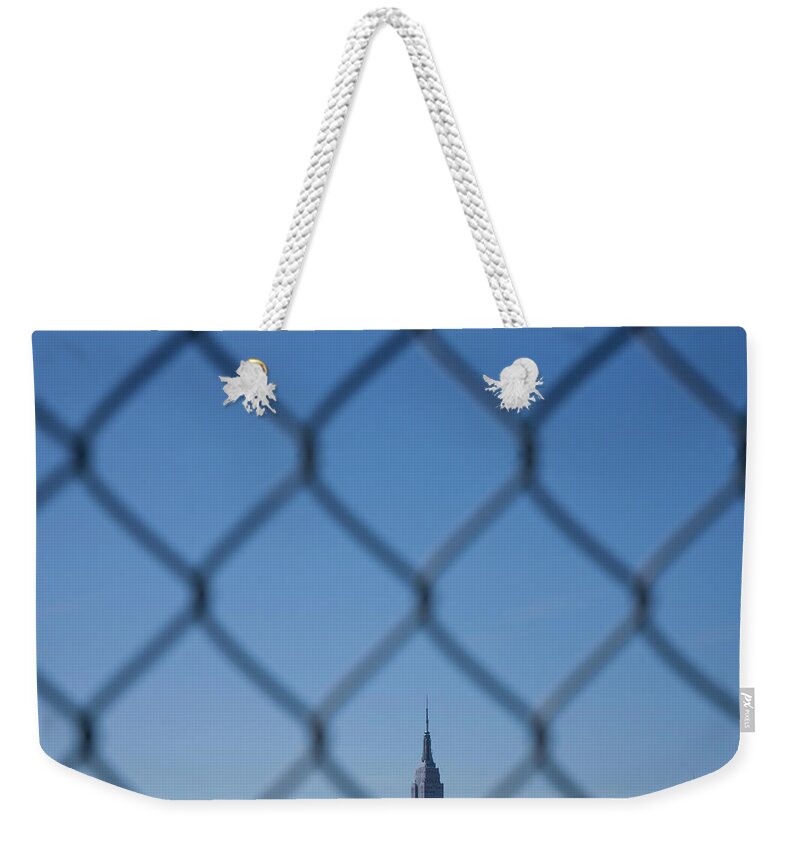 Tranquility Weekender Tote Bag featuring the photograph Manhattan Skyline Through The Fence by Maciej Toporowicz, Nyc