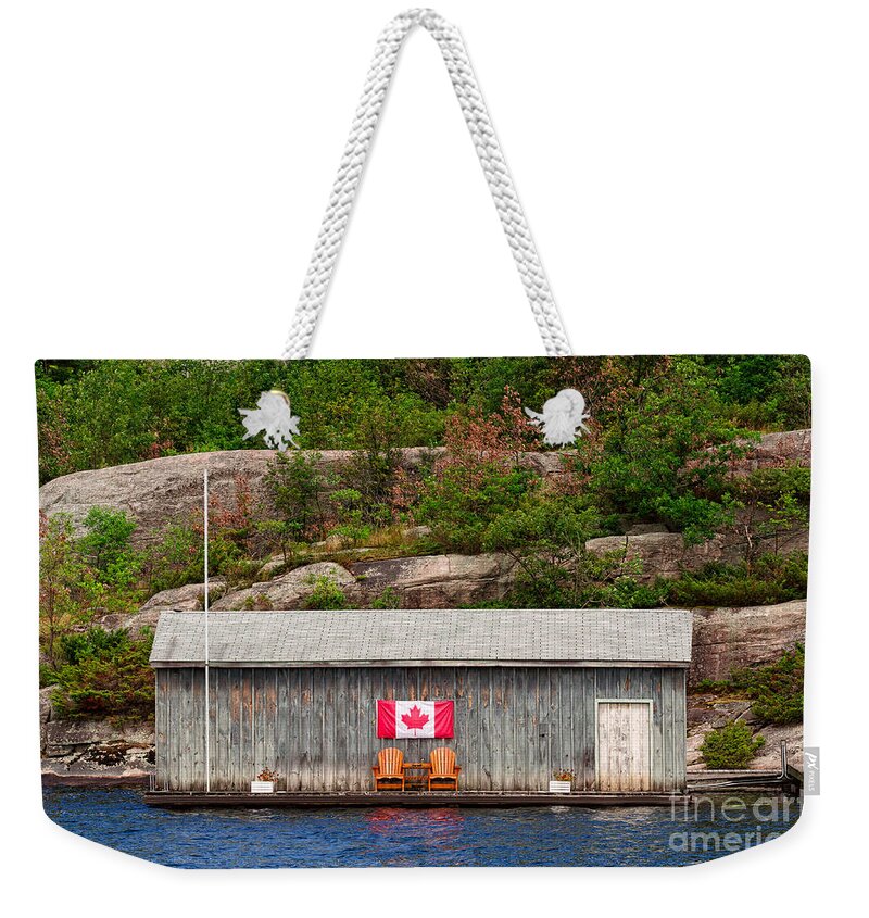 Boathouse Weekender Tote Bag featuring the photograph Old boathouse with two Muskoka chairs by Les Palenik
