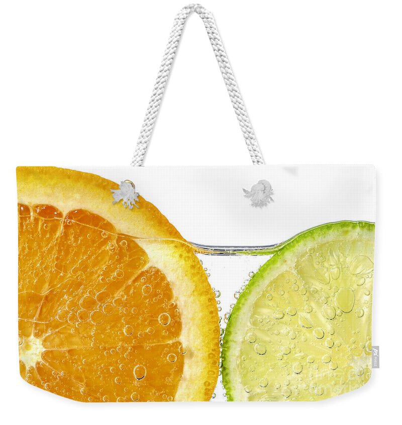 Orange Weekender Tote Bag featuring the photograph Orange and lime slices in water by Elena Elisseeva