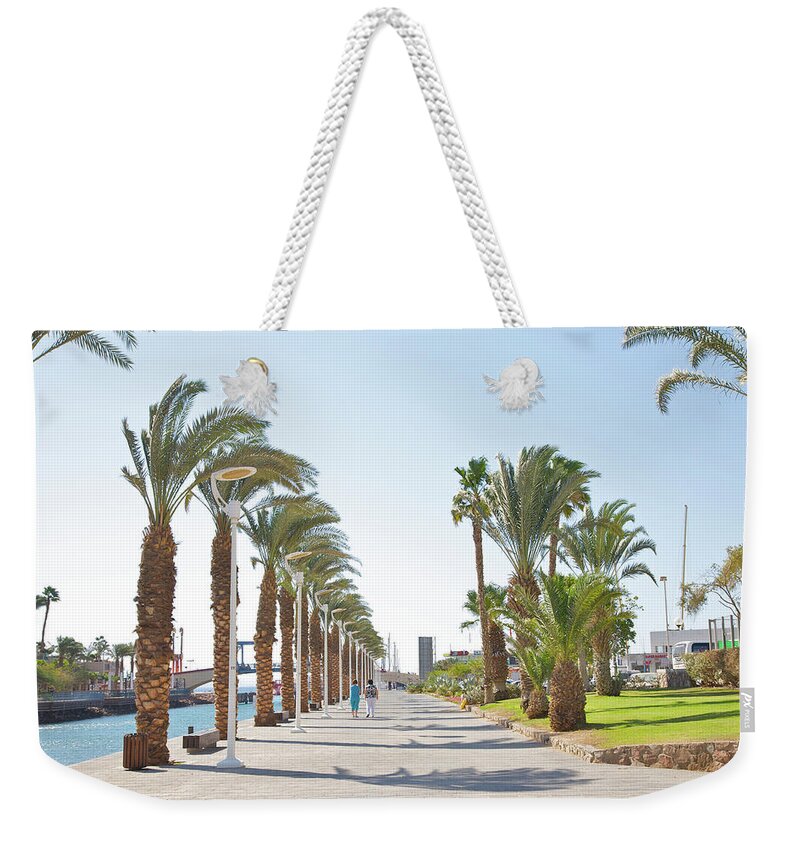 Tranquility Weekender Tote Bag featuring the photograph People In Between Palms On Eilat Walkway by Barry Winiker