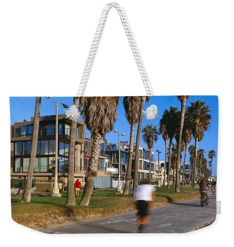 Photography Weekender Tote Bag featuring the photograph People Riding Bicycles Near A Beach by Panoramic Images