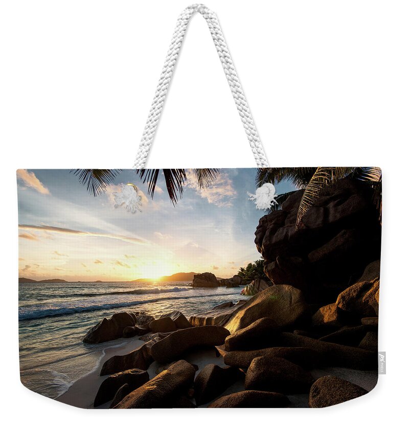 Water's Edge Weekender Tote Bag featuring the photograph Sunrise Framed By Palm Trees And Rock by Pitgreenwood