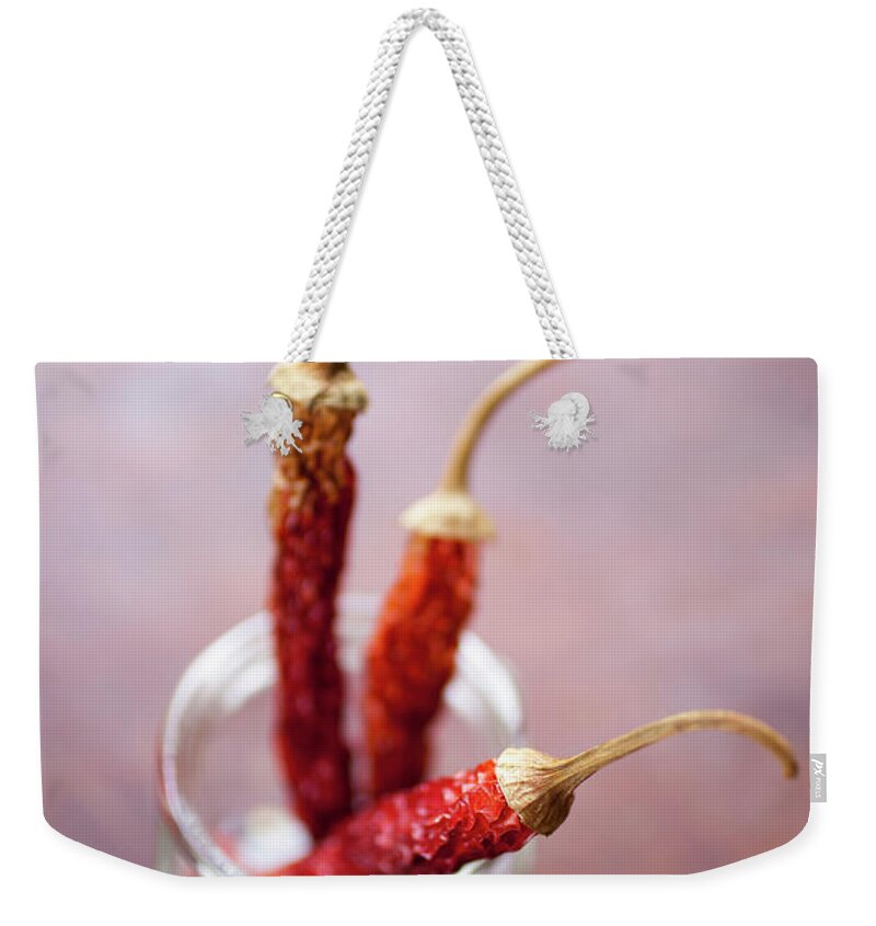 Spice Weekender Tote Bag featuring the photograph Three Dried Chilies In A Glass Jar by Tobias Titz