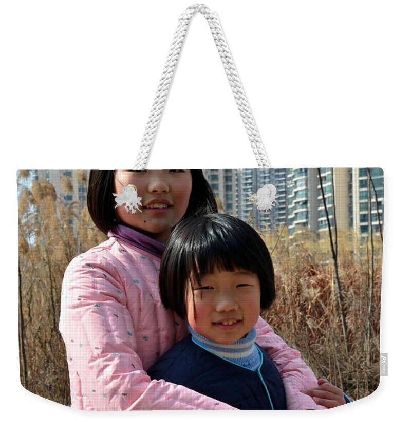 Girls Weekender Tote Bag featuring the photograph Two Chinese teen sisters hug and embrace Shanghai China by Imran Ahmed