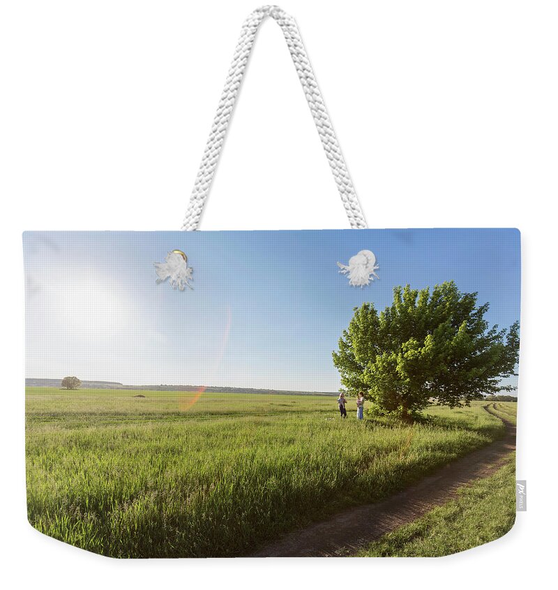 Mature Adult Weekender Tote Bag featuring the photograph Two Mothers Holding Their Babies While by Vladimir Godnik