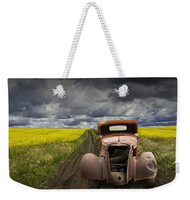 Vintage Weekender Tote Bag featuring the photograph Vintage Chevy Pickup on a dirt path through a canola field by Randall Nyhof