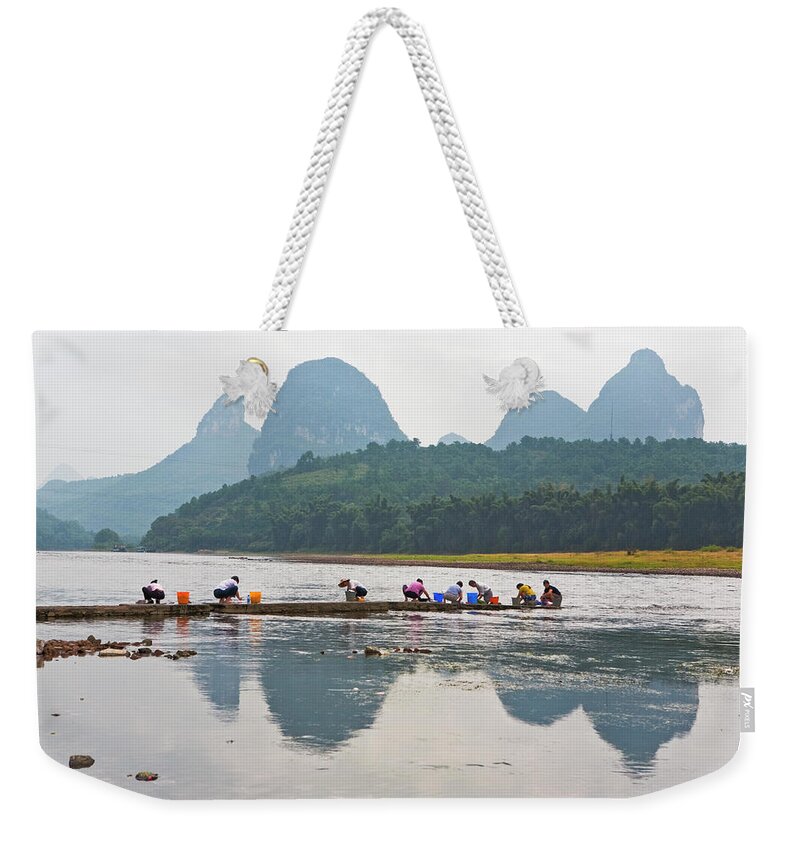 Working Weekender Tote Bag featuring the photograph Women Washing Clothes By Li River With by Merten Snijders
