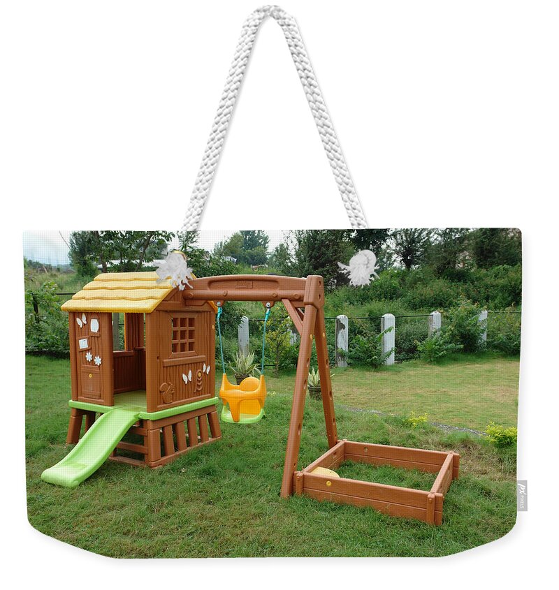 Child Weekender Tote Bag featuring the photograph A childs playing equipment in a green location by Ashish Agarwal