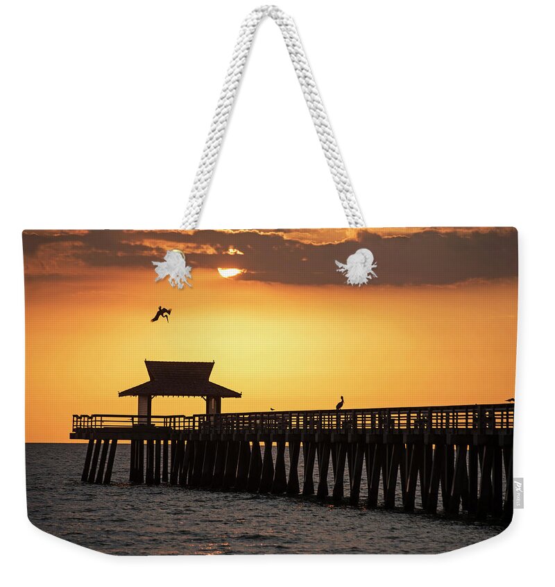 Naples Weekender Tote Bag featuring the photograph A pelican dive-bomb at the Naples Pier Naples FL by Toby McGuire