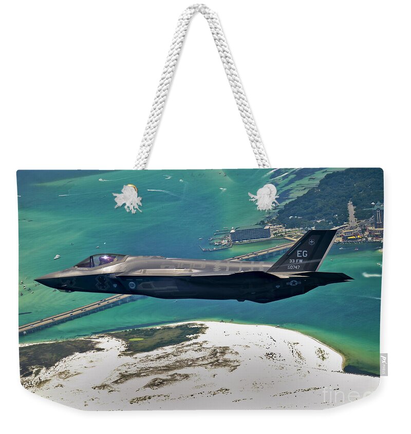 Stealth Weekender Tote Bag featuring the photograph An F-35 Lightning II Flies Over Destin by Stocktrek Images