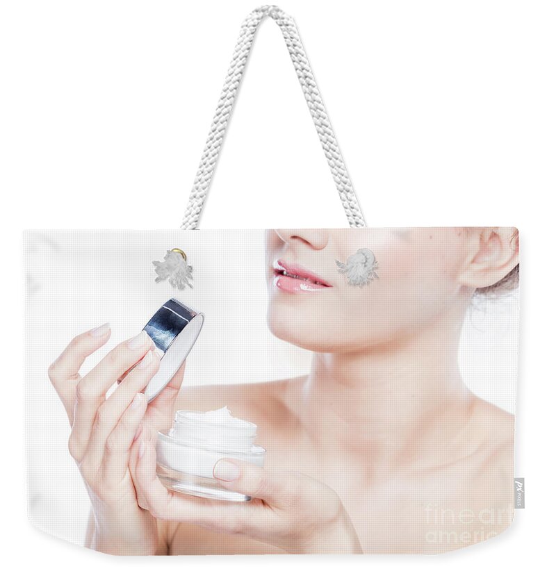 Skincare Weekender Tote Bag featuring the photograph Attractive woman opening a face cream. by Michal Bednarek