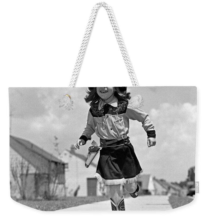 1950s Weekender Tote Bag featuring the photograph Cowgirl Running Down Sidewalk, C.1950s by H. Armstrong Roberts/ClassicStock