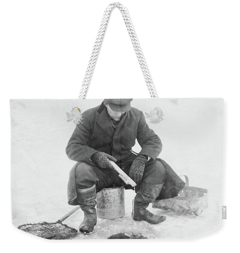 Man Ice Fishing Weekender Tote Bag featuring the photograph Fishing through Ice by Anthony Murphy
