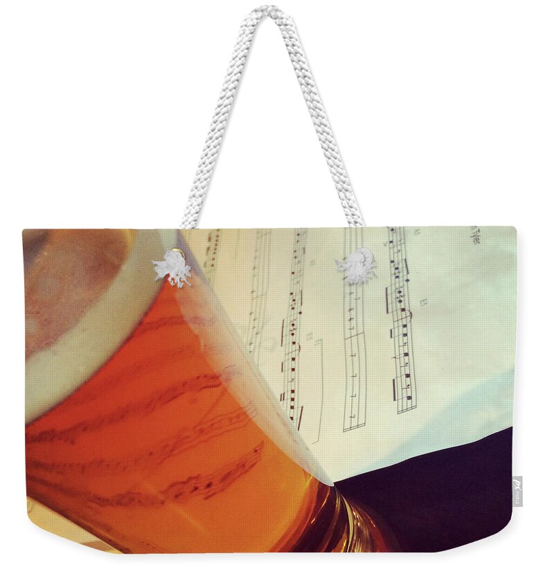 Beer Weekender Tote Bag featuring the photograph Glass of beer and music notes by GoodMood Art